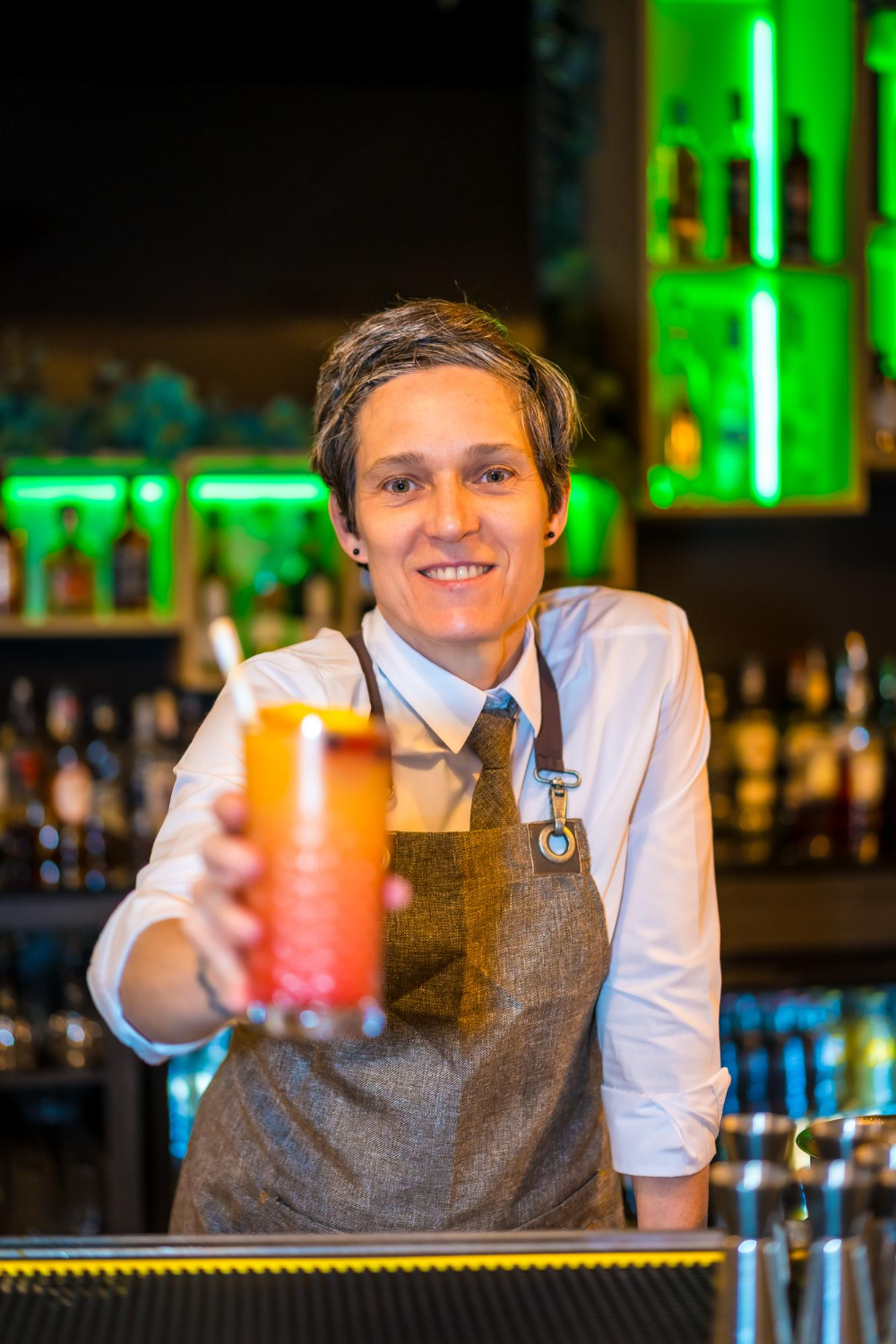 portrait vertical barman heureux servant cocktail luxe au comptoir bar